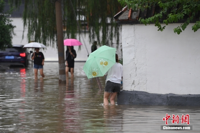 7月31日，市民行走在雨中的北京房山區(qū)瓦窯頭村。北京市氣象臺當(dāng)日10時發(fā)布分區(qū)域暴雨紅色預(yù)警信號。北京市水文總站發(fā)布洪水紅色預(yù)警，預(yù)計當(dāng)日12時至14時，房山區(qū)大石河流域?qū)⒊霈F(xiàn)紅色預(yù)警標(biāo)準(zhǔn)洪水。<a target='_blank' href='/'><p  align=