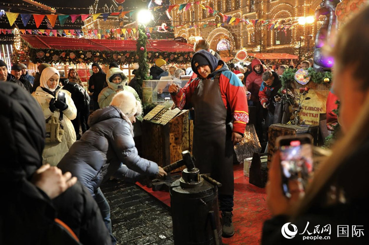 游客在新年集市上體驗(yàn)制作紀(jì)念幣。人民網(wǎng)記者 隋鑫攝