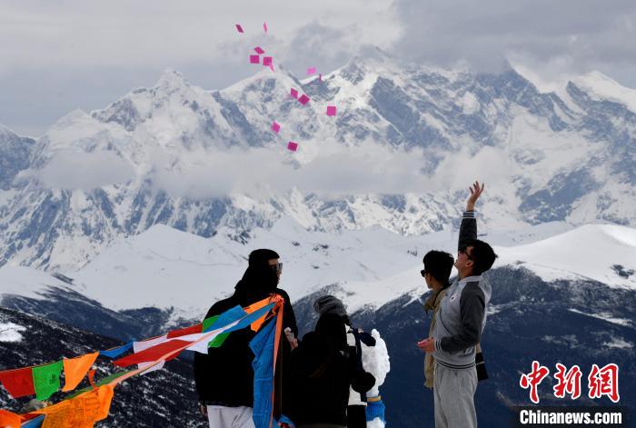 圖為5月14日，游客在西藏林芝色季拉山觀景臺拋灑“隆達”(風馬旗，藏族民眾的一種祈福方式)?！±盍?攝