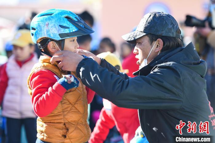 圖為拉薩市實(shí)驗(yàn)幼兒園孩子在教練的幫助下穿戴頭盔?！『闻罾?攝