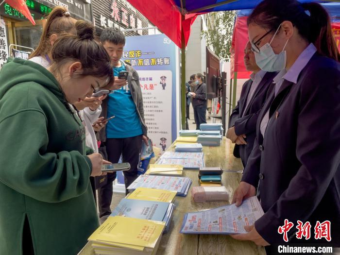 圖為工作人員正在向路過(guò)市民介紹國(guó)家反詐中心軟件的功能。　謝牧 攝